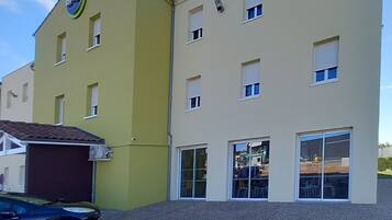 A two-story building with a yellow facade and a sign indicating a business or service.
