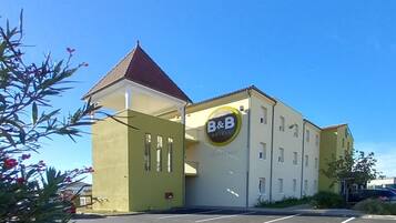 A B&B hotel with a yellow facade, a red roof, and a sign with 'B&B' and 'Bienvenue'.