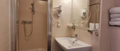 A bathroom with a shower, sink, toilet, and a mirror.