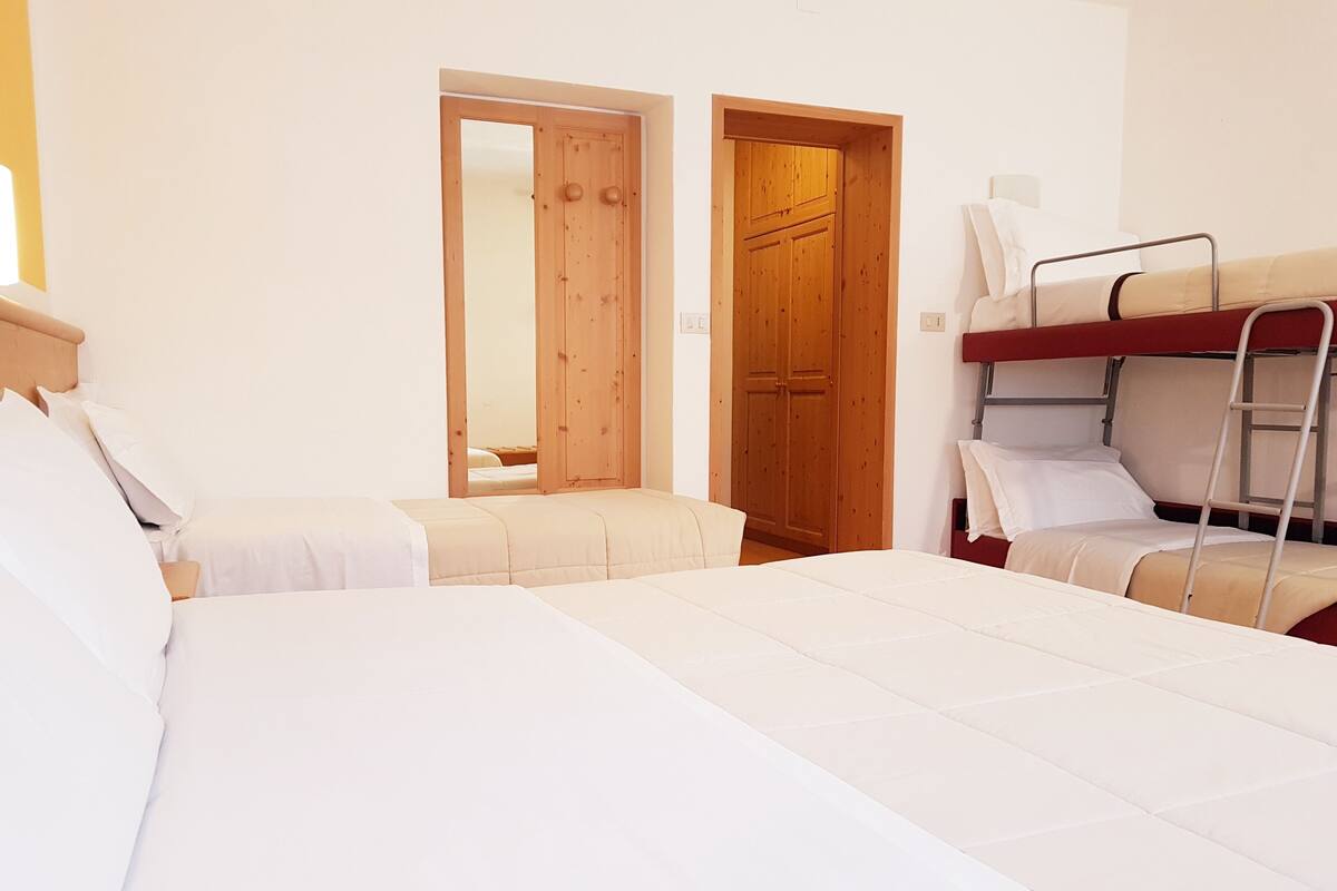 A room with two beds, a wooden wardrobe, and a ladder.