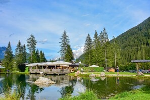 A lakeside resort with outdoor seating and a wooden deck overlooking the water. - San Giusto (Falcade)