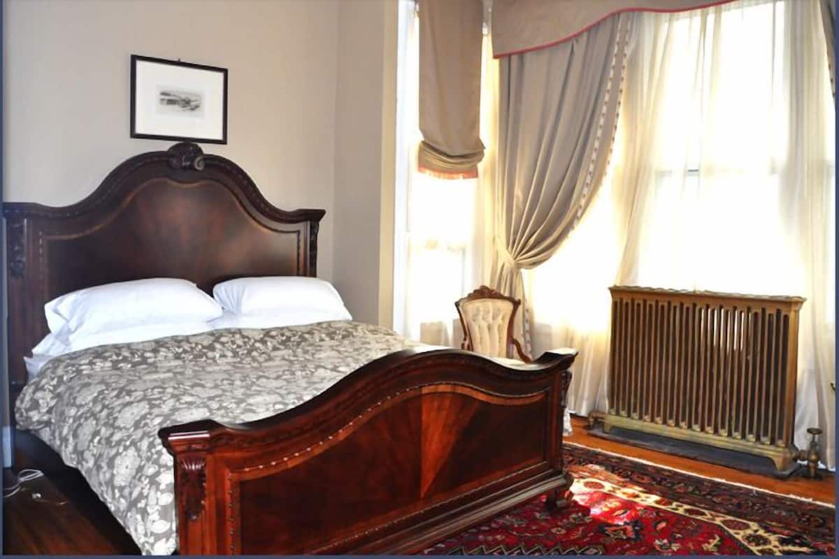 Un dormitorio con una cama de madera, un radiador y un tapete estampado.