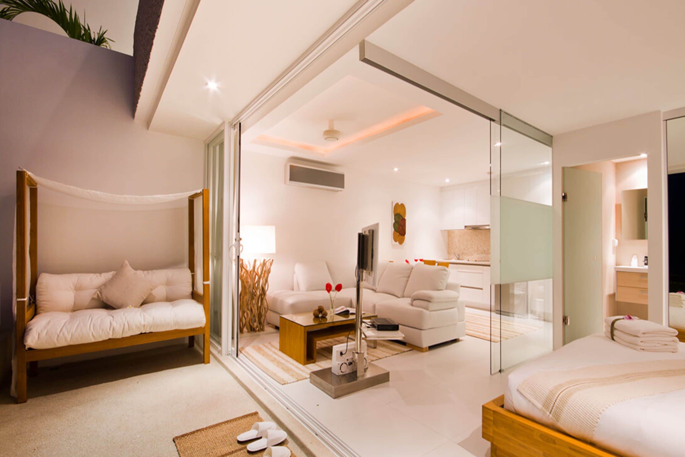 A modern hotel room with a bed, a sofa, a coffee table, and a TV.
