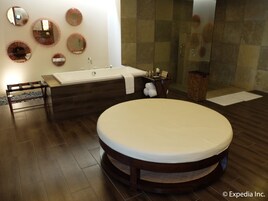 Un baño moderno con una bañera redonda grande, una zona de ducha independiente y varios espejos en la pared.