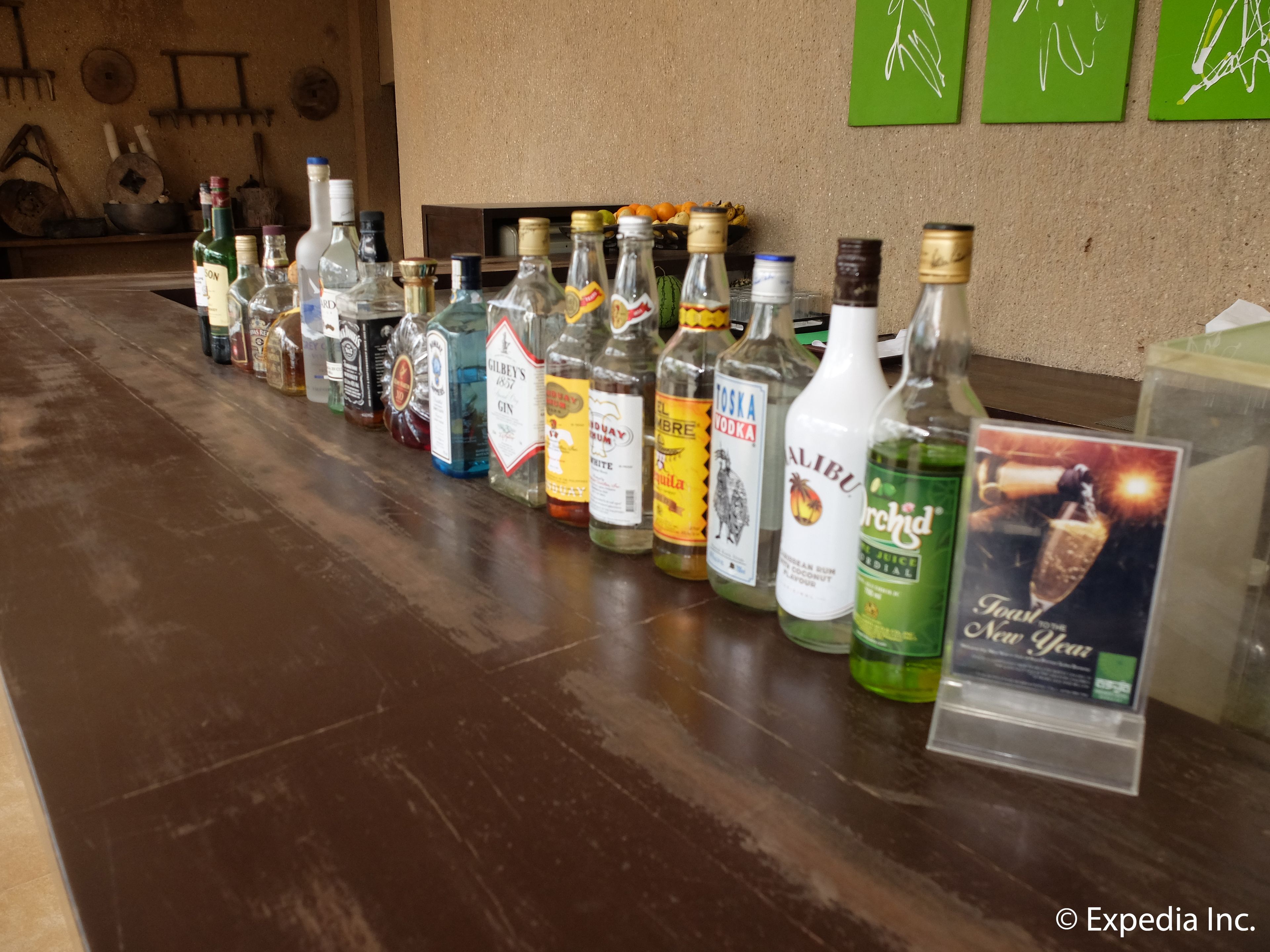 A bar with various liquor bottles lined up on a wooden counter.