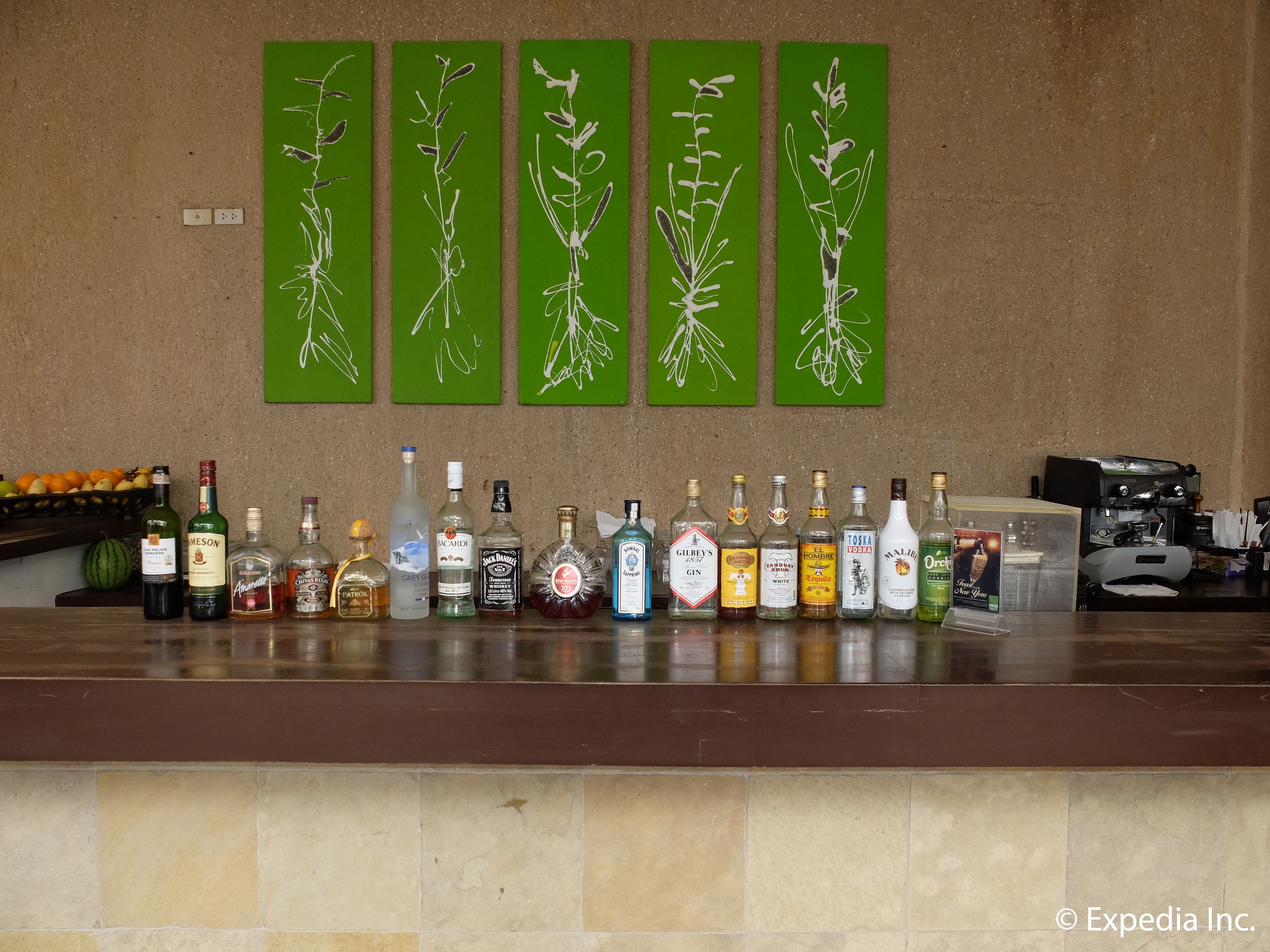 A bar with various liquor bottles and green artwork on the wall.