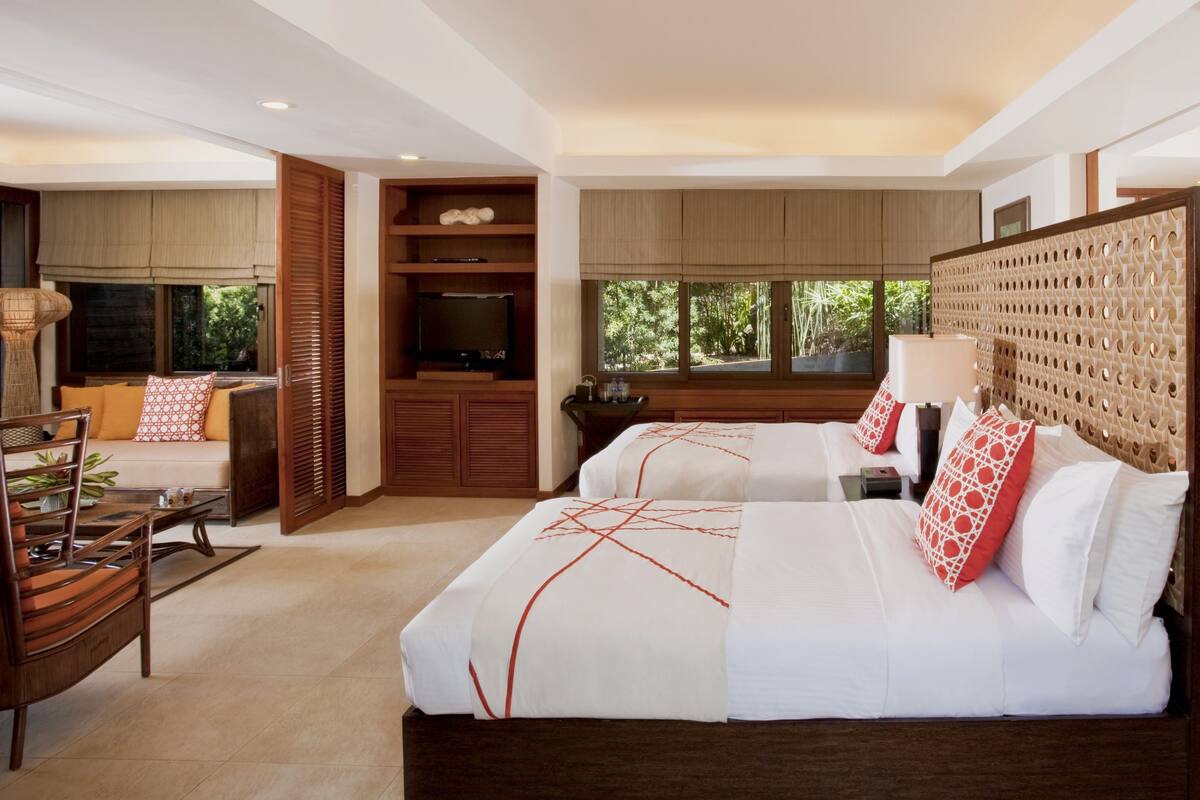 A modern hotel room with a large bed, a seating area, and a view of the outdoors.