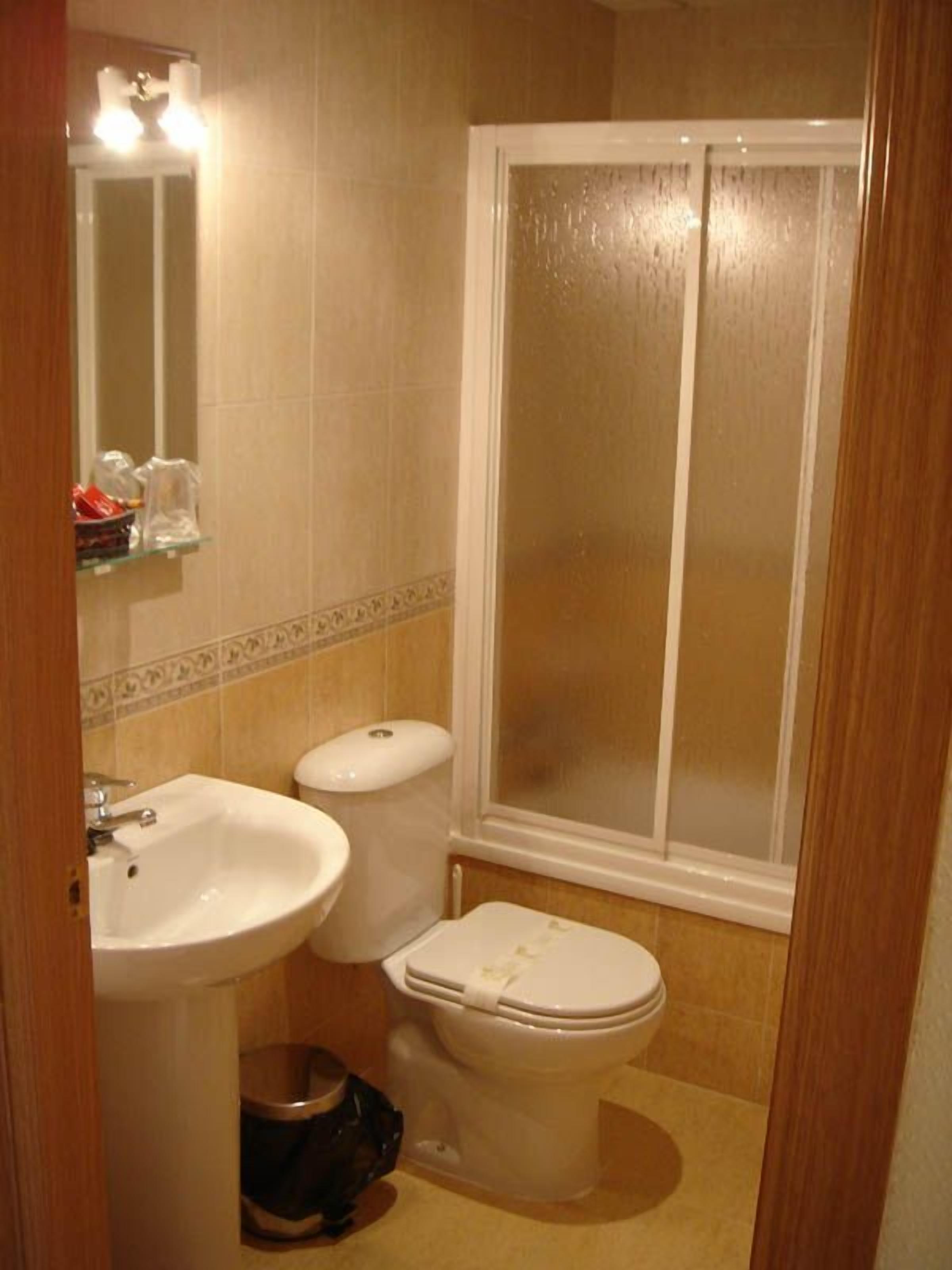 Et badeværelse med vask, toilet og brusekabine.