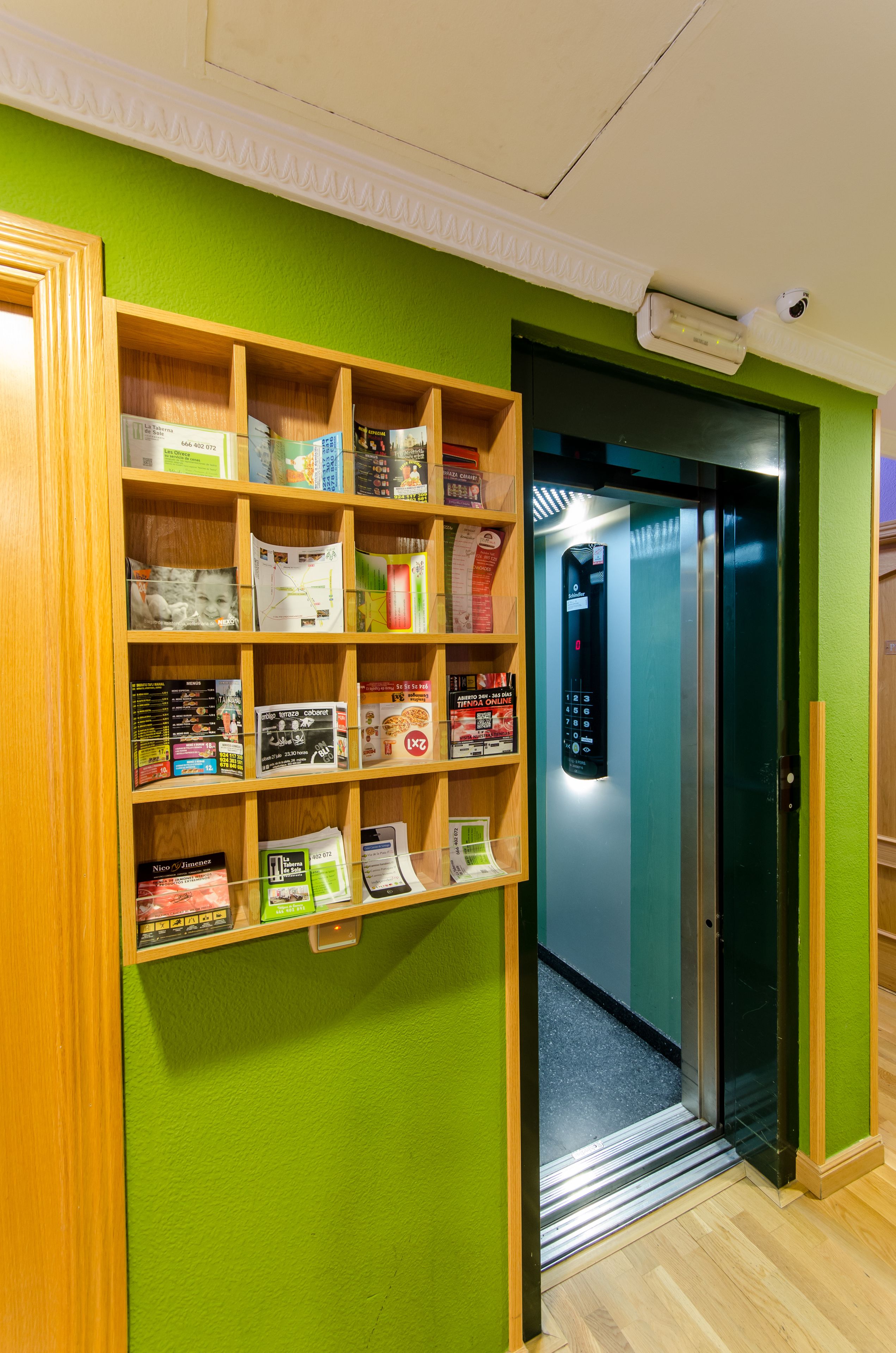 Un mur végétal agrémenté d’une étagère en bois remplie de magazines et de livres.