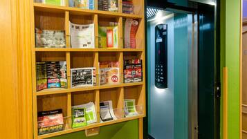 Un mur végétal agrémenté d’une étagère en bois remplie de magazines et de livres.
