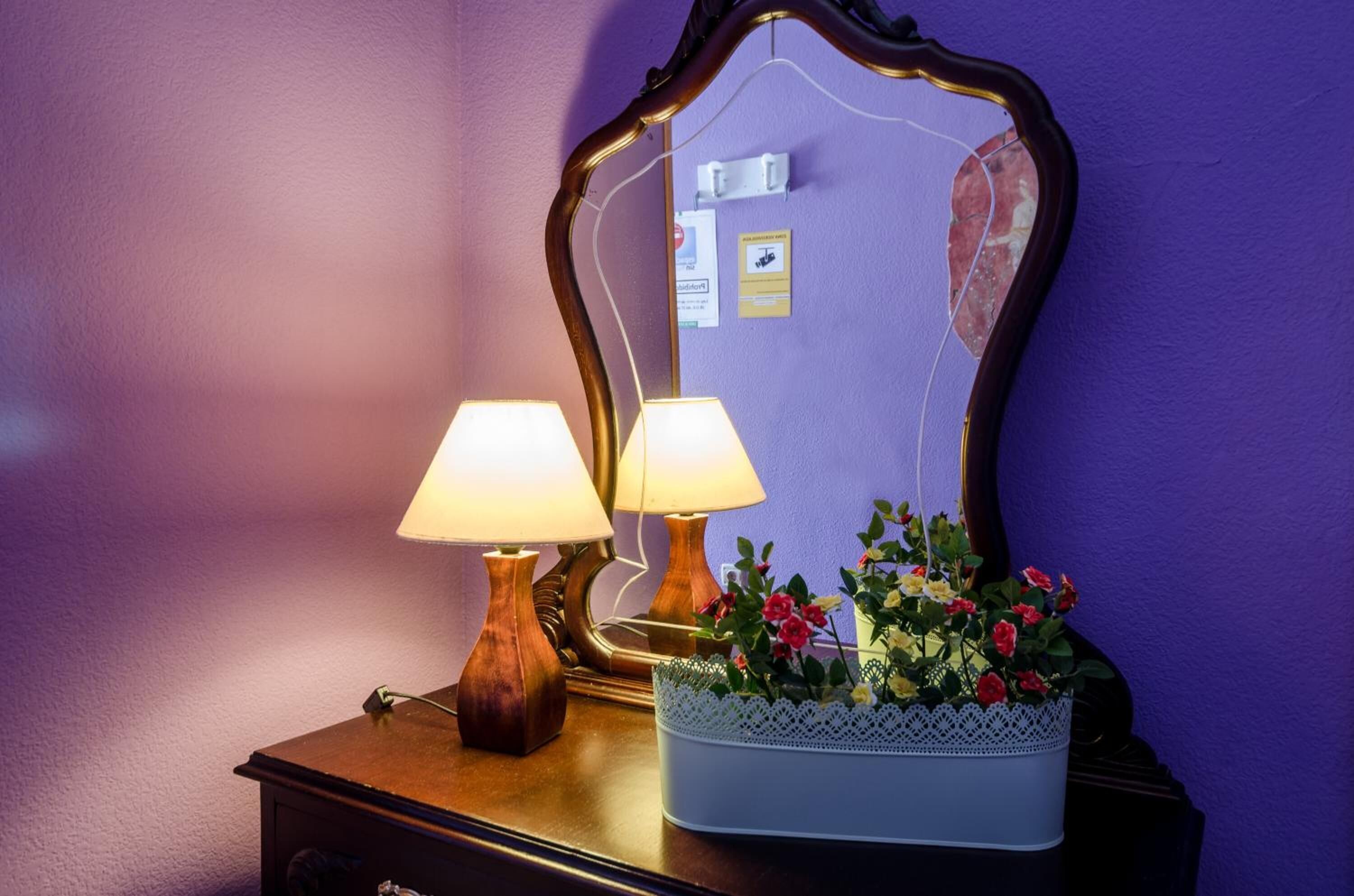 A wooden dresser with two lamps and a mirror.