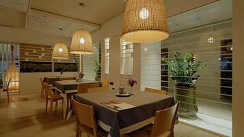 A dining area with a table set for four, surrounded by chairs, and large woven pendant lights above.