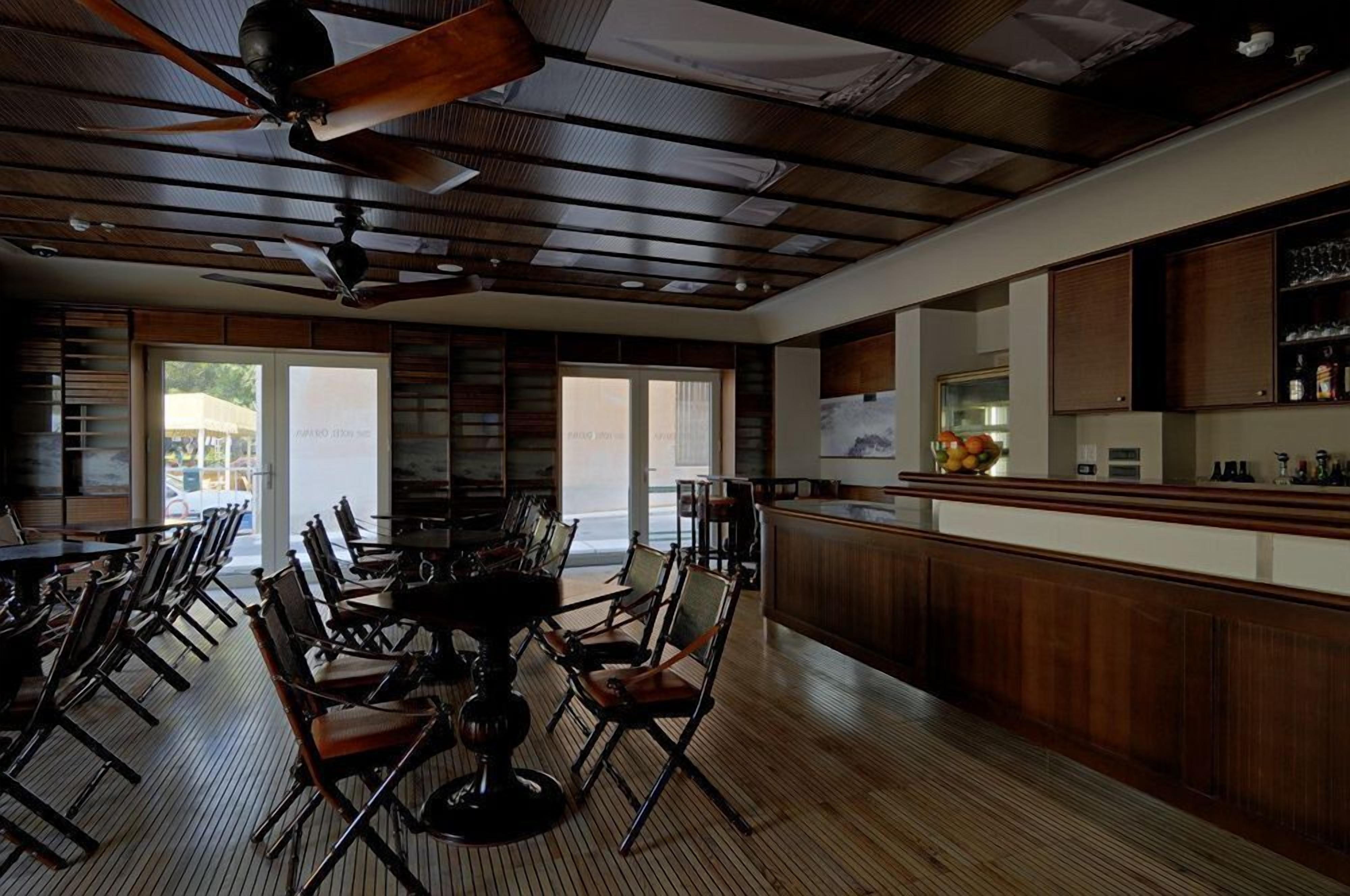 En restaurant med træloft, barområde og spiseområde med stole og borde.