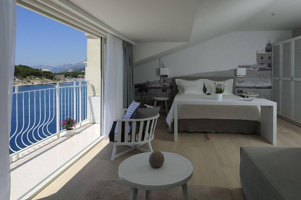 A modern hotel room with a balcony overlooking a body of water and mountains.