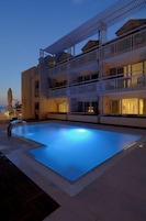 Una piscina al aire libre, sillones reclinables de piscina