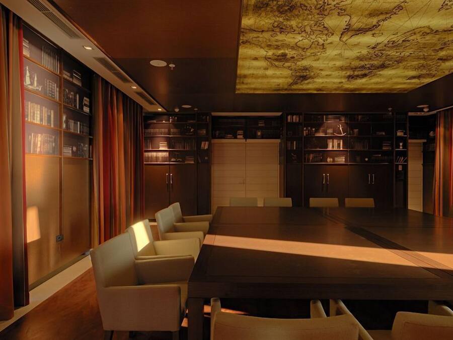 Una biblioteca moderna con una gran mesa de madera y sillones de cuero, rodeada de estanterías.