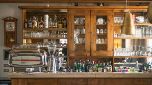 A bar area with wooden cabinets, shelves with liquor bottles, glasses, and a vintage espresso machine. - Park Hotel Elefante (Verona)