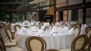 A round dining table set for a formal event, surrounded by upholstered chairs. - Park Hotel Elefante (Verona)