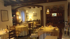 A restaurant with round tables, chairs, and a wine rack. - Park Hotel Elefante (Verona)