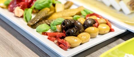 A buffet with various food items including olives, pickles, and vegetables.