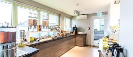 Une cuisine moderne dotée d’un long comptoir, de différents distributeurs d’aliments et d’une machine à café.