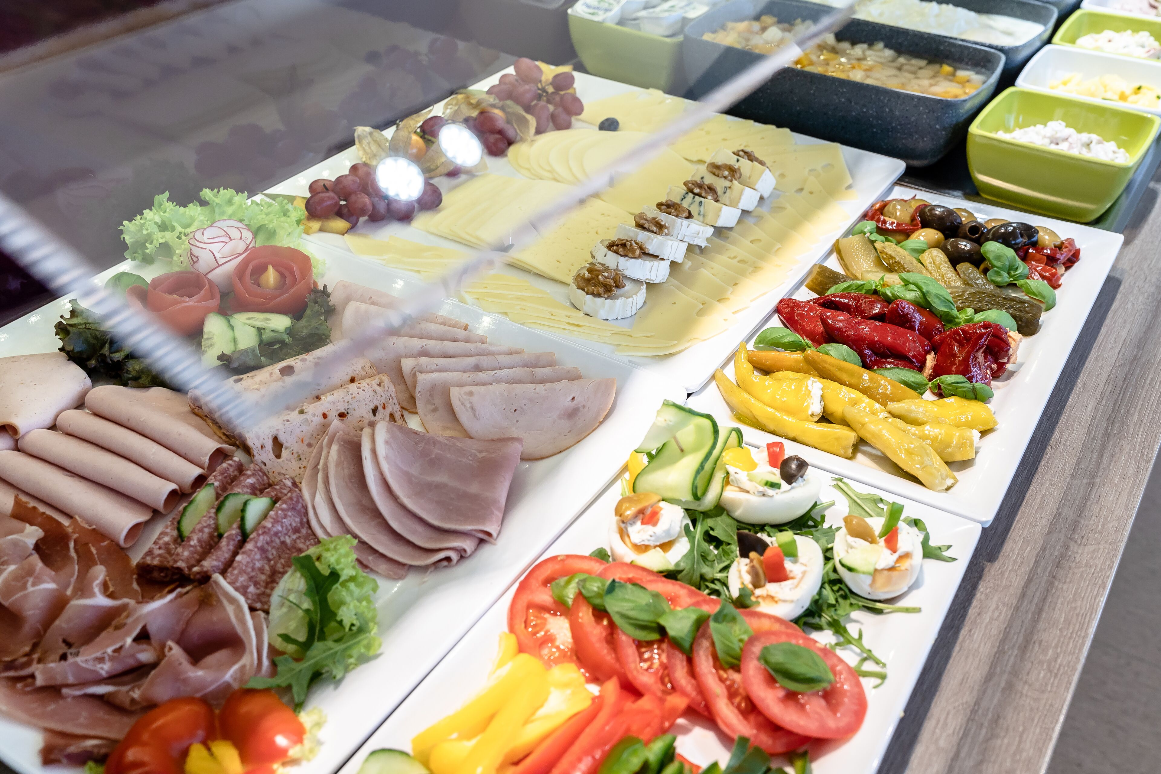 Un bufé con diversas opciones de comida, incluyendo carnes, quesos y ensaladas.