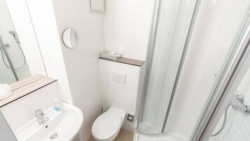Ein modernes Badezimmer mit Waschbecken, Toilette und Duschkabine aus Glas.