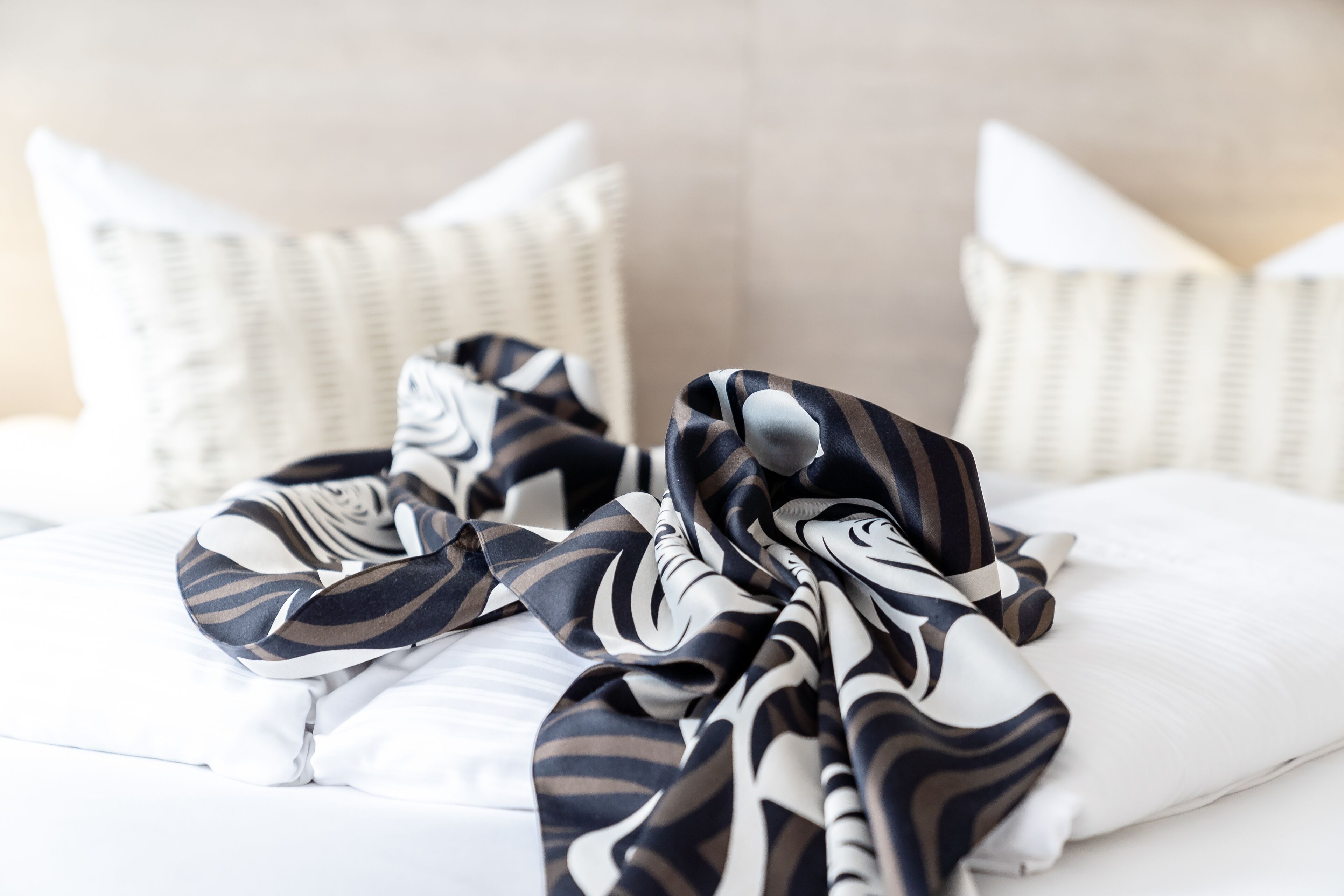 A neatly made bed with white bedding and a striped blanket.