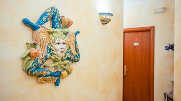 Een decoratief wandobject met een deur en een wandlamp op de achtergrond.
