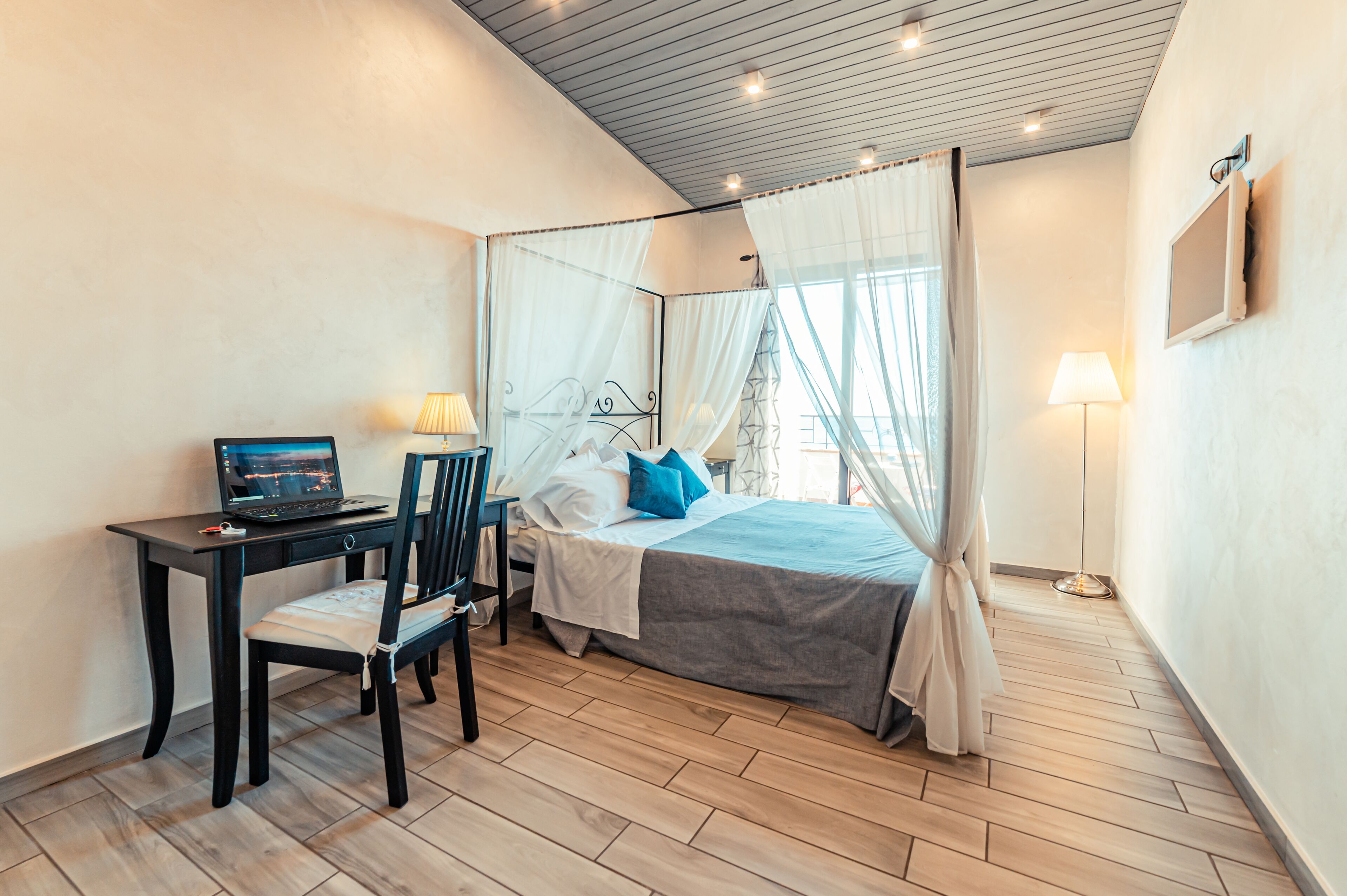 A bedroom with a bed, a desk, a chair, and a laptop.