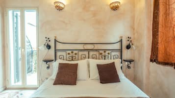 Un dormitorio con cama, dos apliques de pared, una ventana y una cortina.