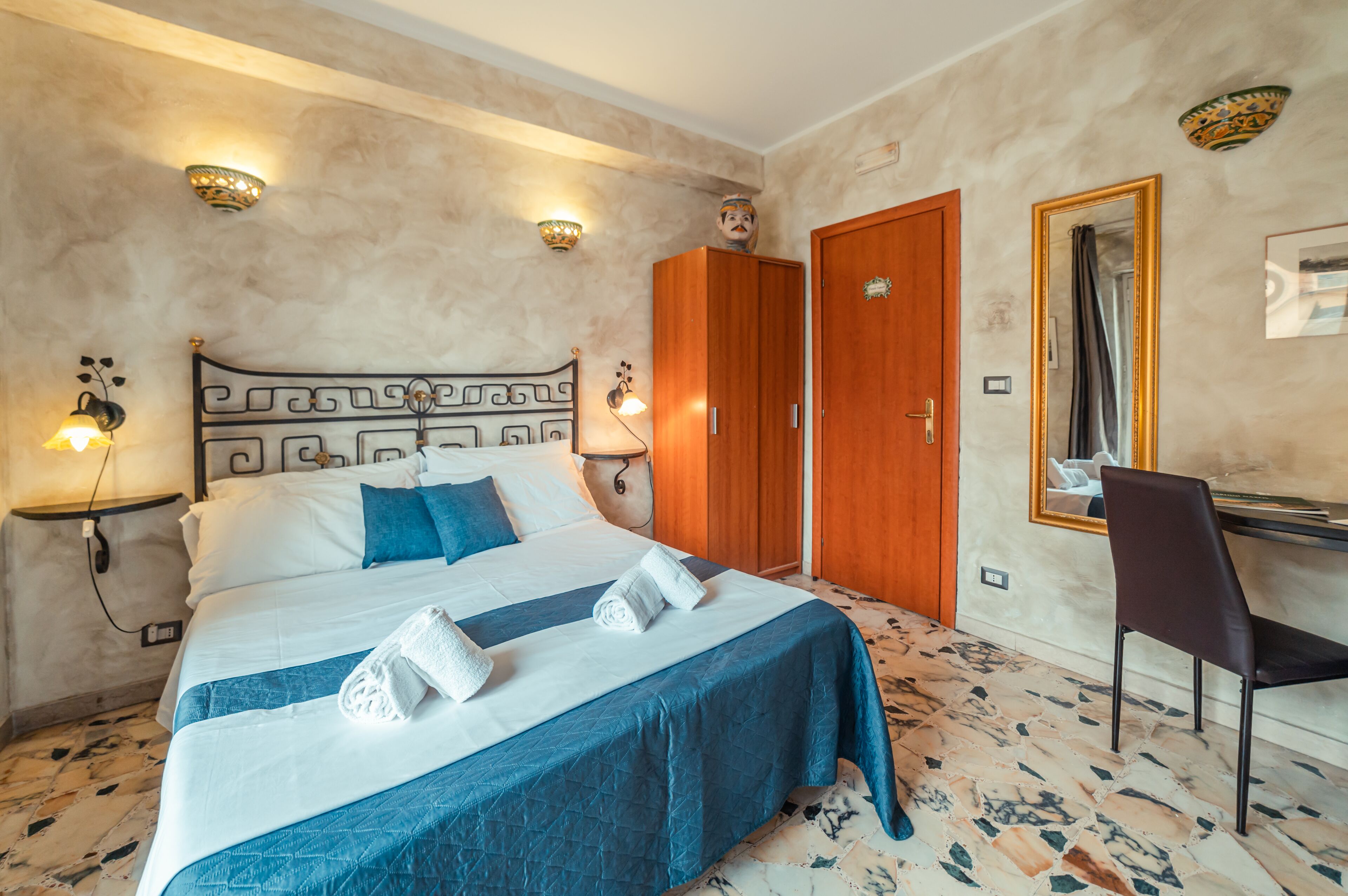 A hotel room with a bed, a desk, a chair, and a wardrobe.