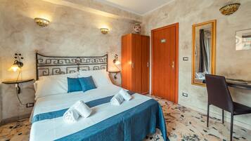 A hotel room with a bed, a desk, a chair, and a wardrobe.