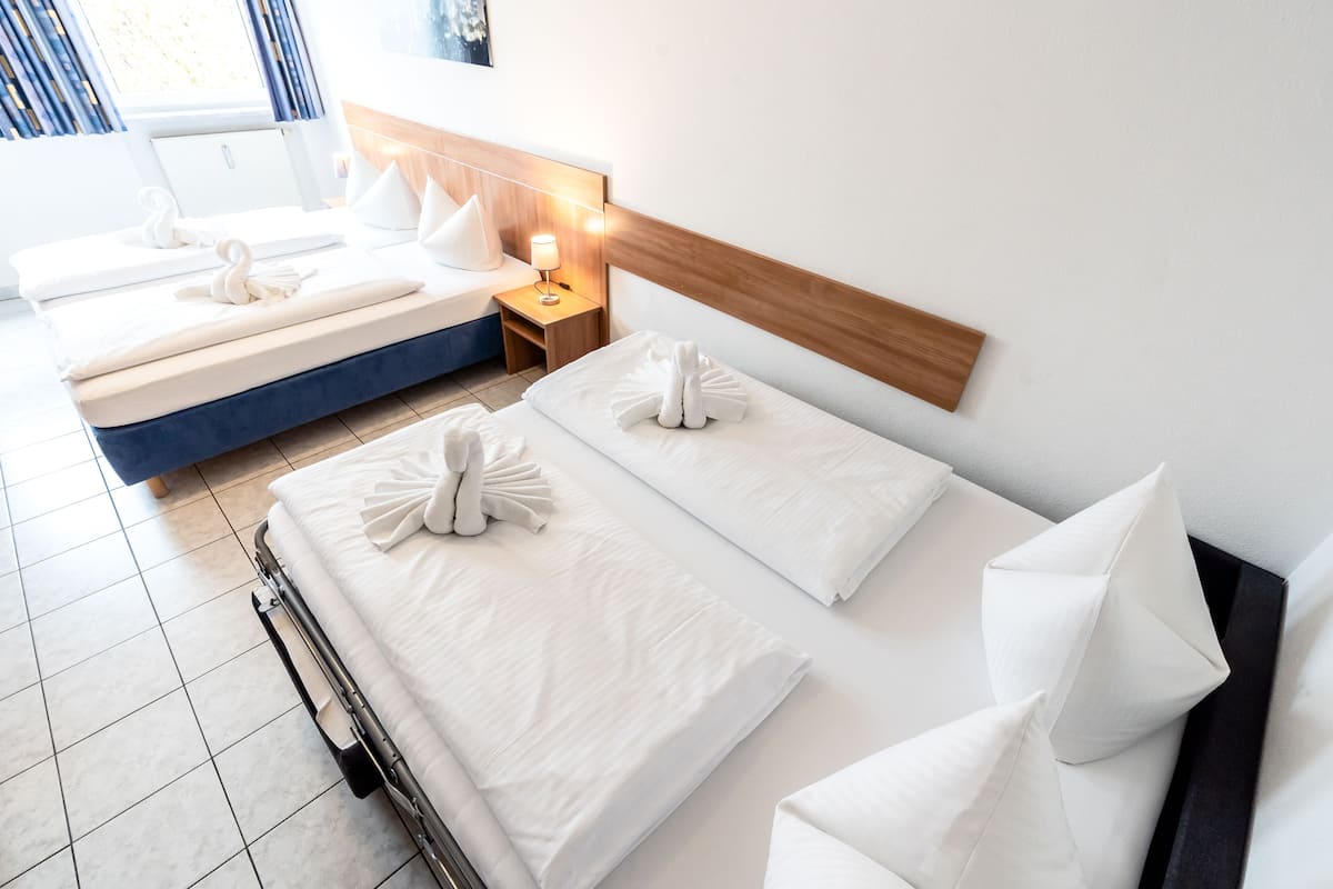 A hotel room with two beds, each with neatly arranged towels and pillows.