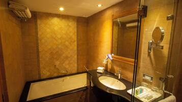 A bathroom with a bathtub, a sink, a mirror, and a shower area.