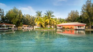Ein Resort mit Pool, Palmen und Gebäuden mit roten Dächern.