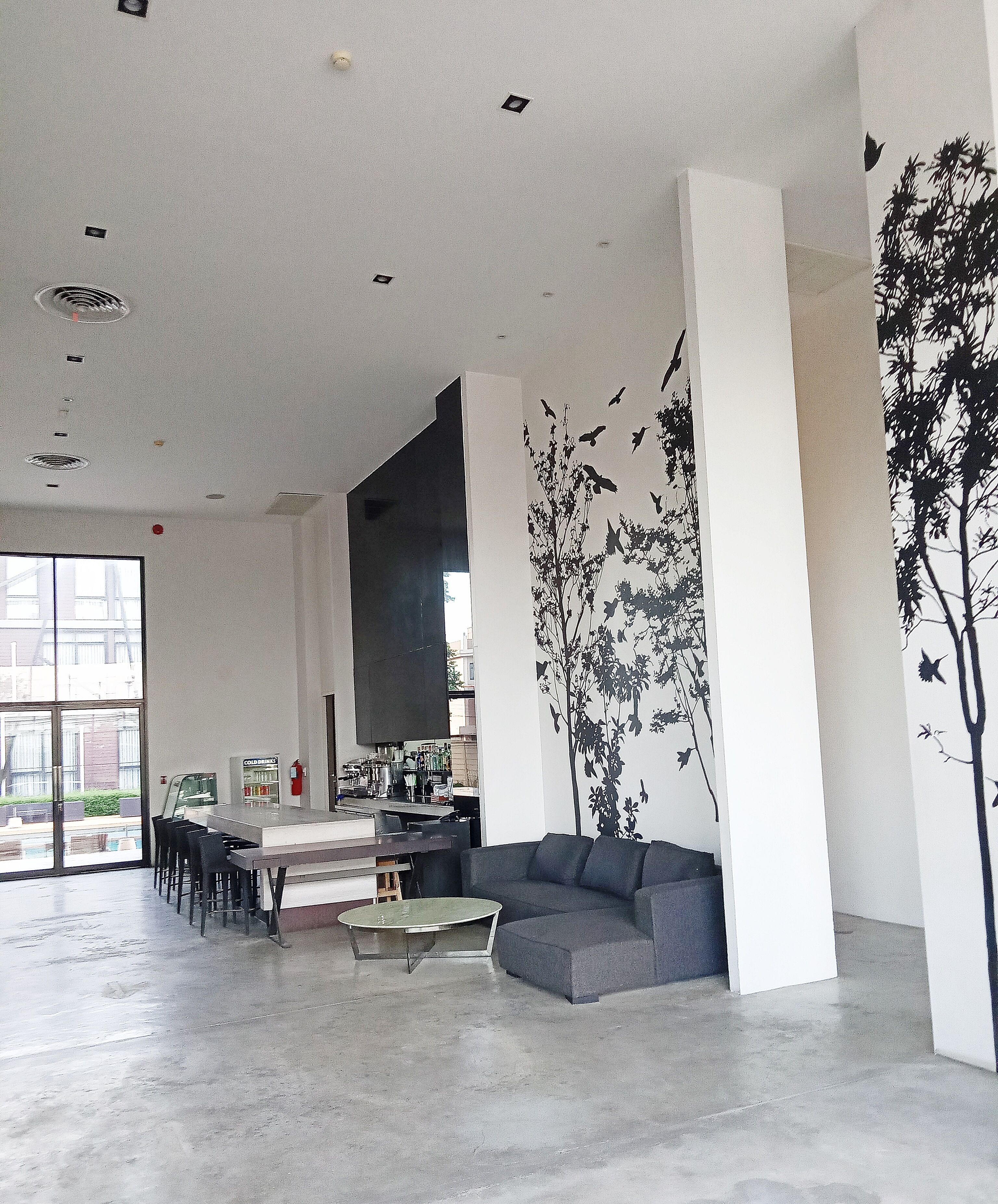 A spacious living area with a modern sofa, a dining table with chairs, and a kitchen in the background.
