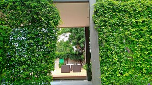 An outdoor area with a covered walkway, surrounded by lush green foliage. - Vismaya Suvarnabhumi Hotel (Bang Phli)