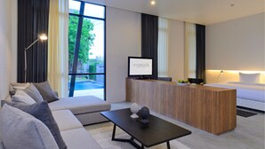 A modern hotel room with a sofa, a coffee table, a reception desk, and a bed. - Vismaya Suvarnabhumi Hotel (Bang Phli)