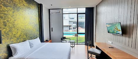 Una habitación de hotel moderna con una cama grande, un escritorio con televisor de pantalla plana y vista a una piscina.