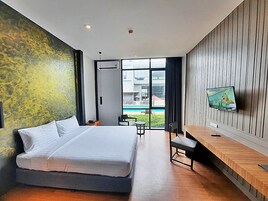 Una habitación de hotel moderna con una cama grande, un escritorio con televisor de pantalla plana y vista a una piscina.