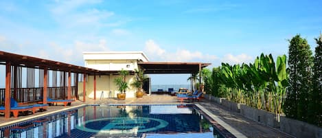 Alberca al aire libre, sombrillas en la alberca y camastros