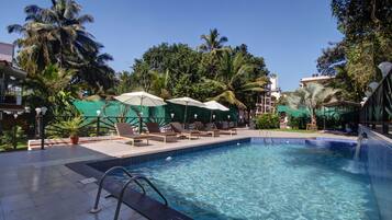 Relax by the pool surrounded by lush greenery and comfortable lounge chairs.