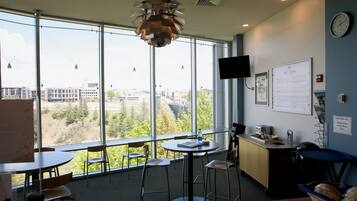 Un espacio de oficina moderno con ventanas amplias, un reloj y una pizarra de menú.