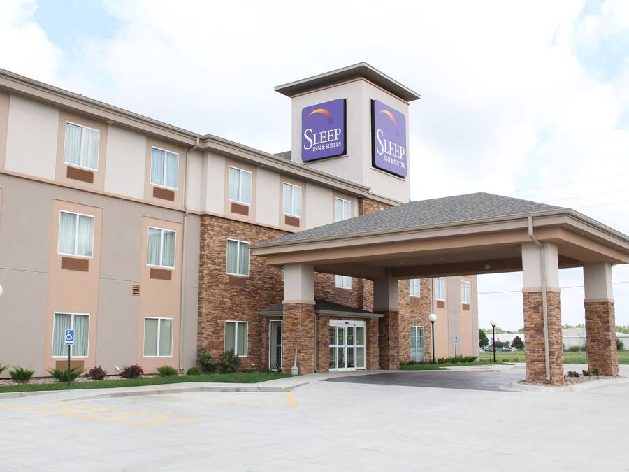 Un hôtel Sleep Inn & Suites avec une façade en briques, de nombreuses fenêtres et une entrée abritée.