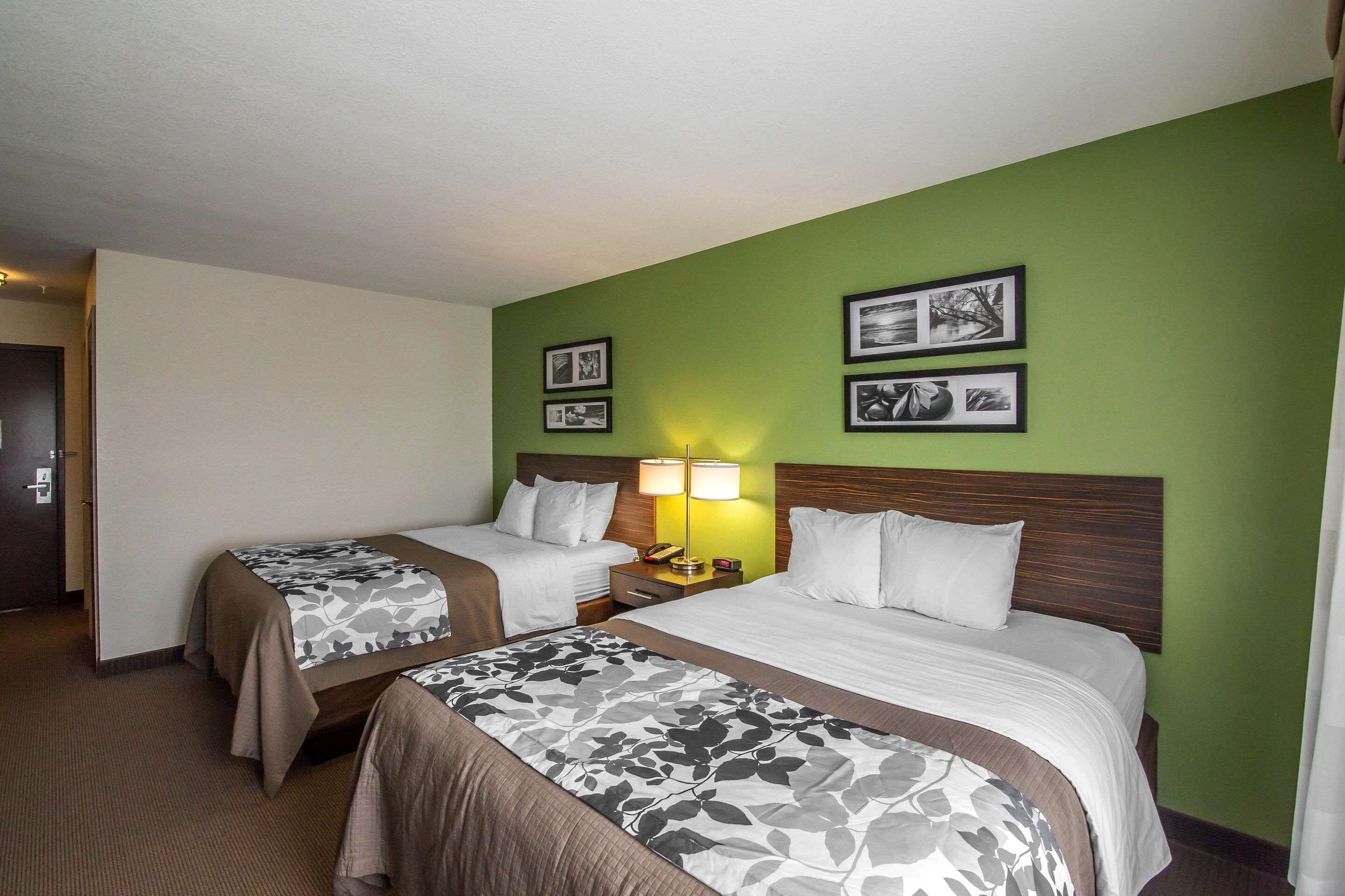 A hotel room with two beds, a nightstand with lamps, and framed pictures on the wall.
