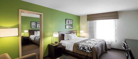 Una habitación de hotel con cama, mesitas de noche, escritorio, silla y un espejo grande.