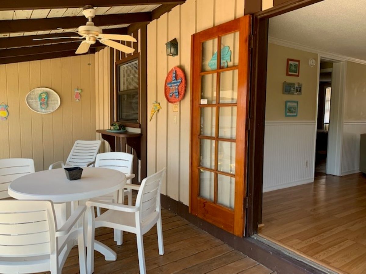 A dining area with a round table and white chairs, a wooden floor, and a wooden-framed door with glass panels.