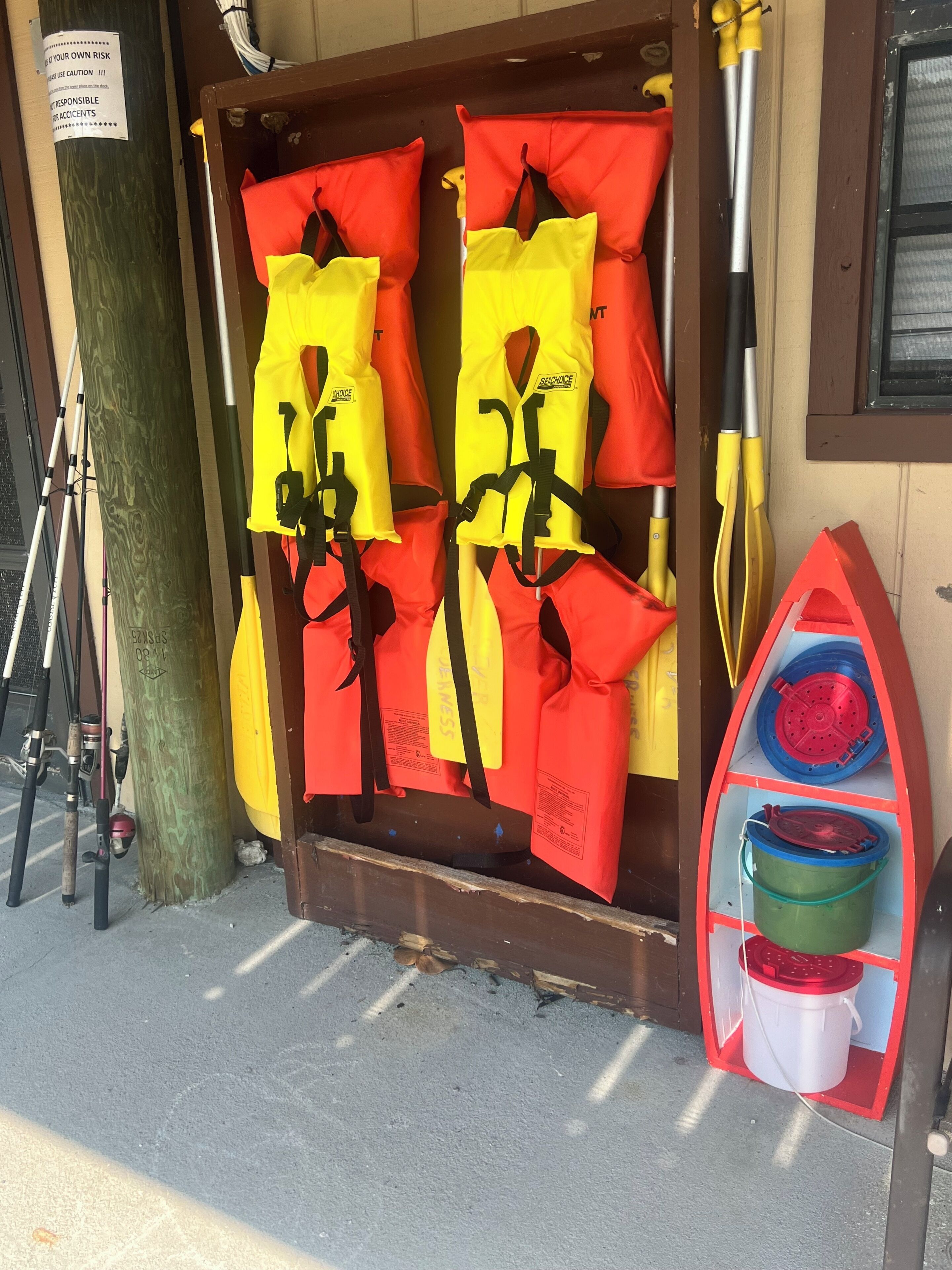 Un espace de rangement contenant des gilets de sauvetage et un kayak rouge.