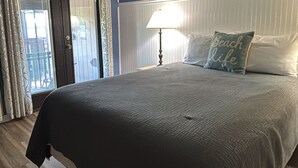 Een slaapkamer met een bed, een plafondventilator, een lamp en een bord waarop 